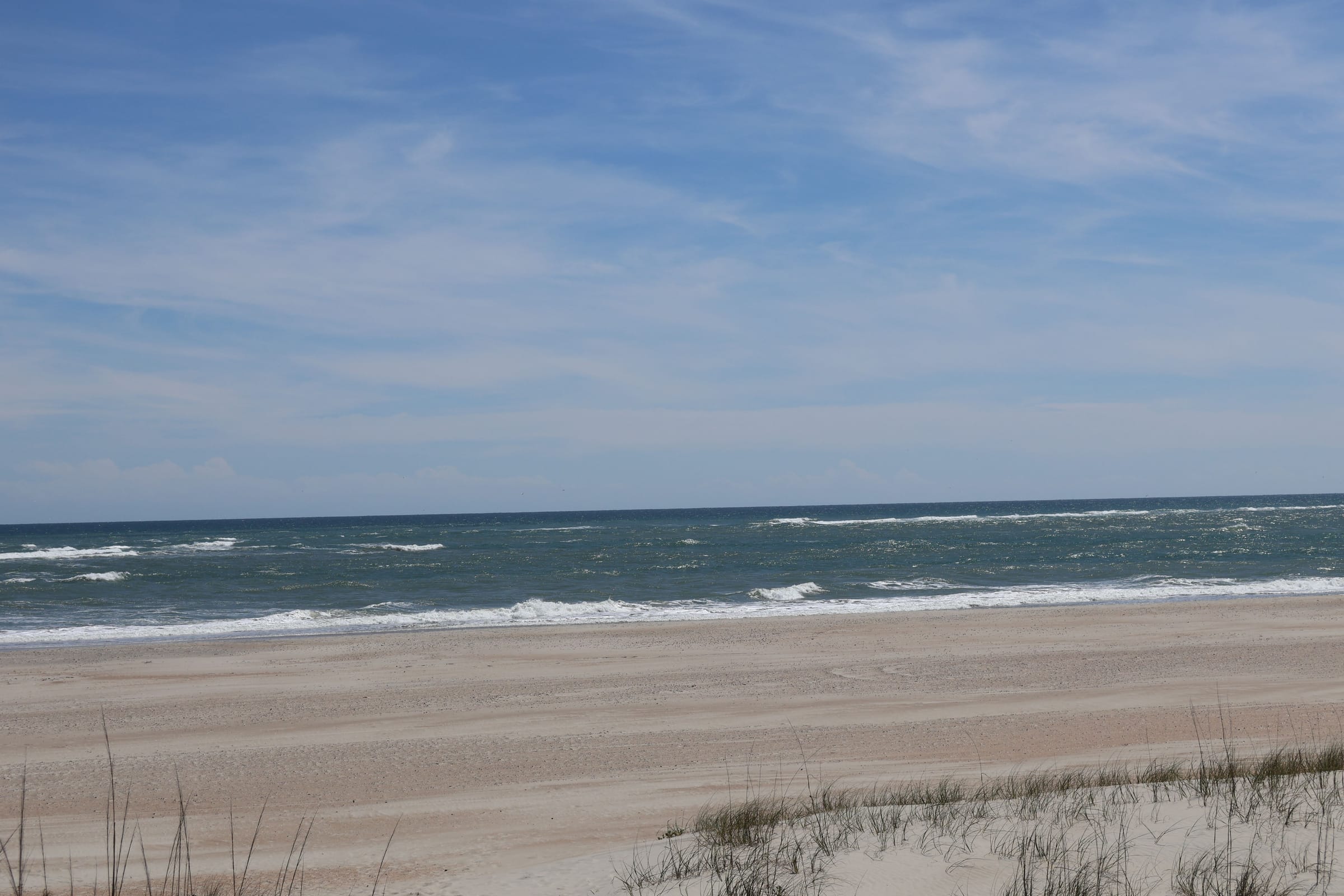 Surf breaking on the beach at Emerald Isle, sea oats in the foreground, a pale sky over the Atlantic