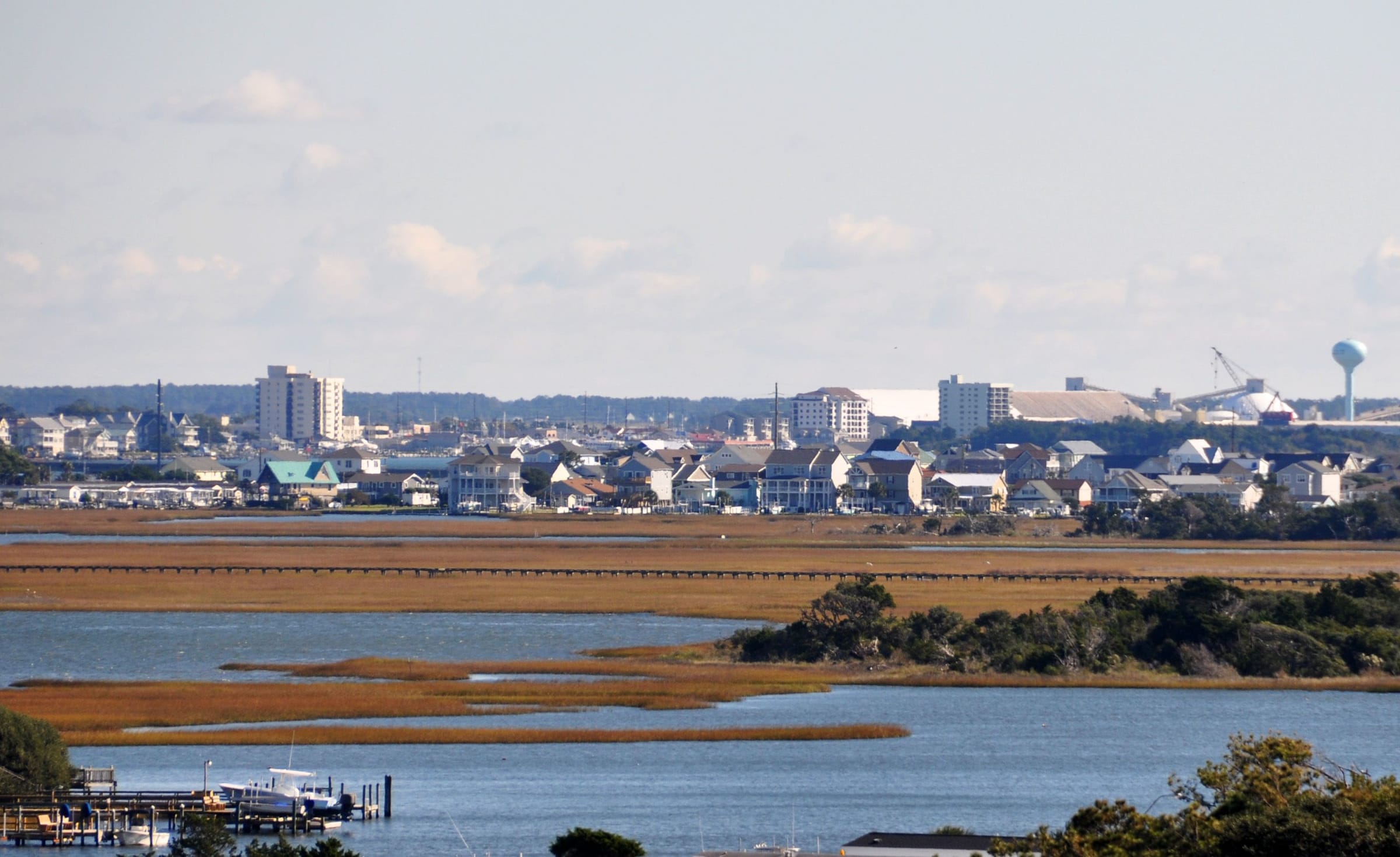 Houses along the Morehead City waterfront seen across the marsh and Bogue Sound from Atlantic Beach, taller buildings behind