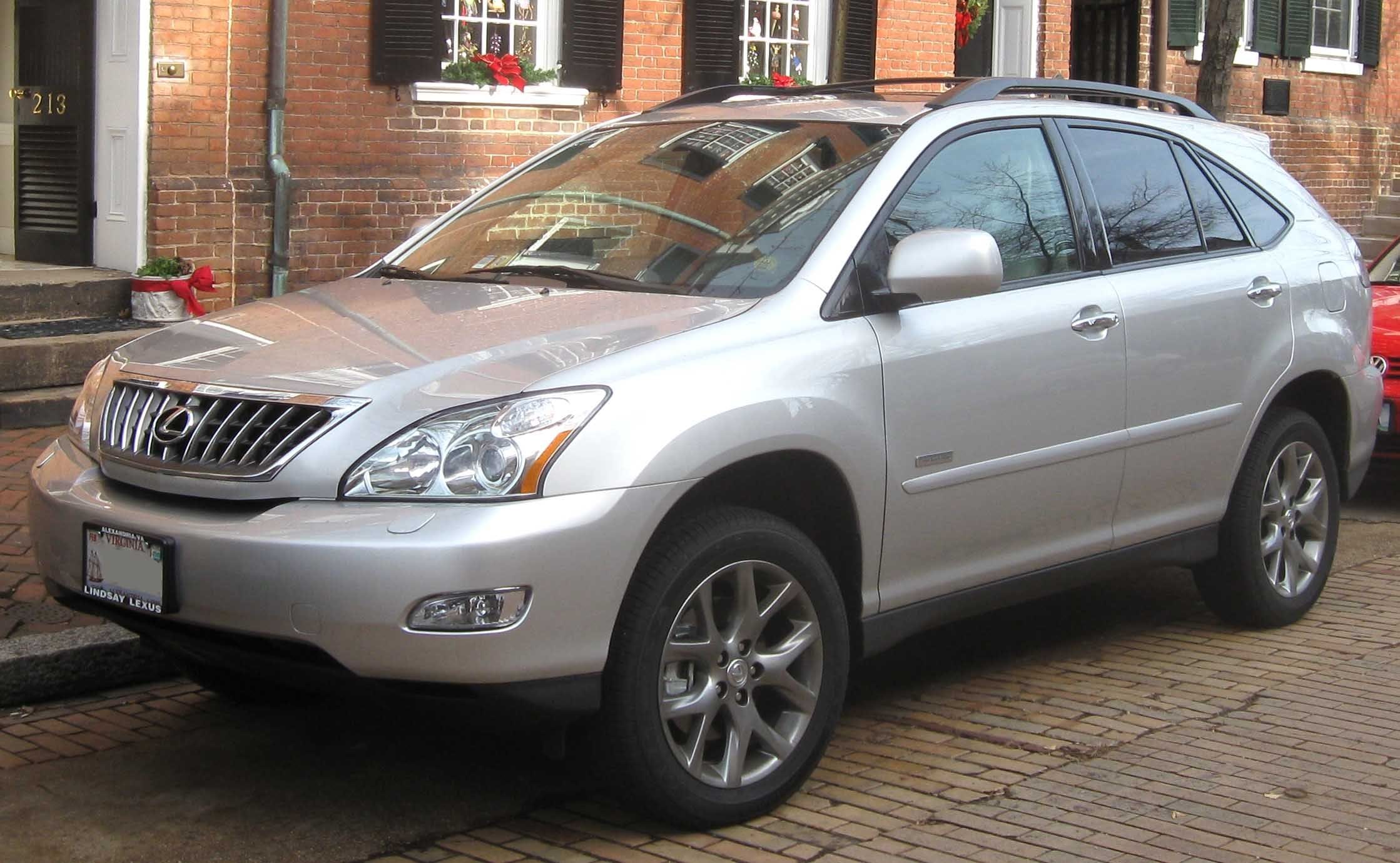 A silver SUV parked on a brick street in front of a brick townhouse