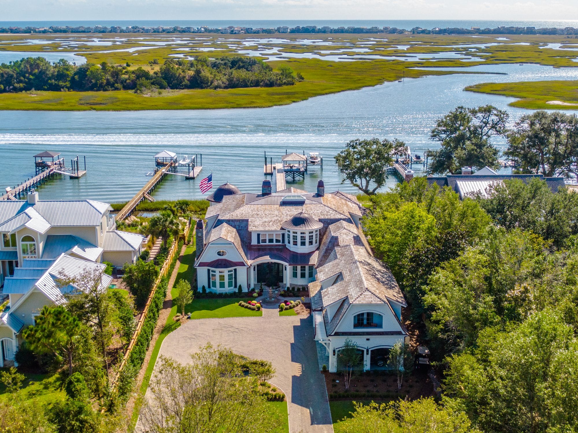 Aerial view of a large new waterfront home with a circular drive, docks and boat lifts on the marsh at Wilmington